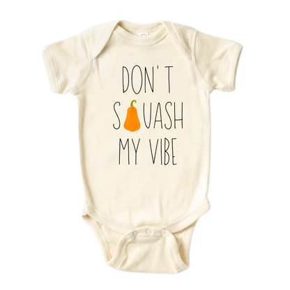 Natural onesie featuring a fall-themed printed graphic of a squash and the fun text 'Don't Squash My Vibe.' Explore this trendy tee, perfect for embracing autumn style. 