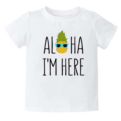 A kids' t-shirt with a pineapple wearing glasses and the text 'Aloha I'm Here.' This fun and tropical design captures the playful spirit, adding a vibrant touch to the wearer's style.