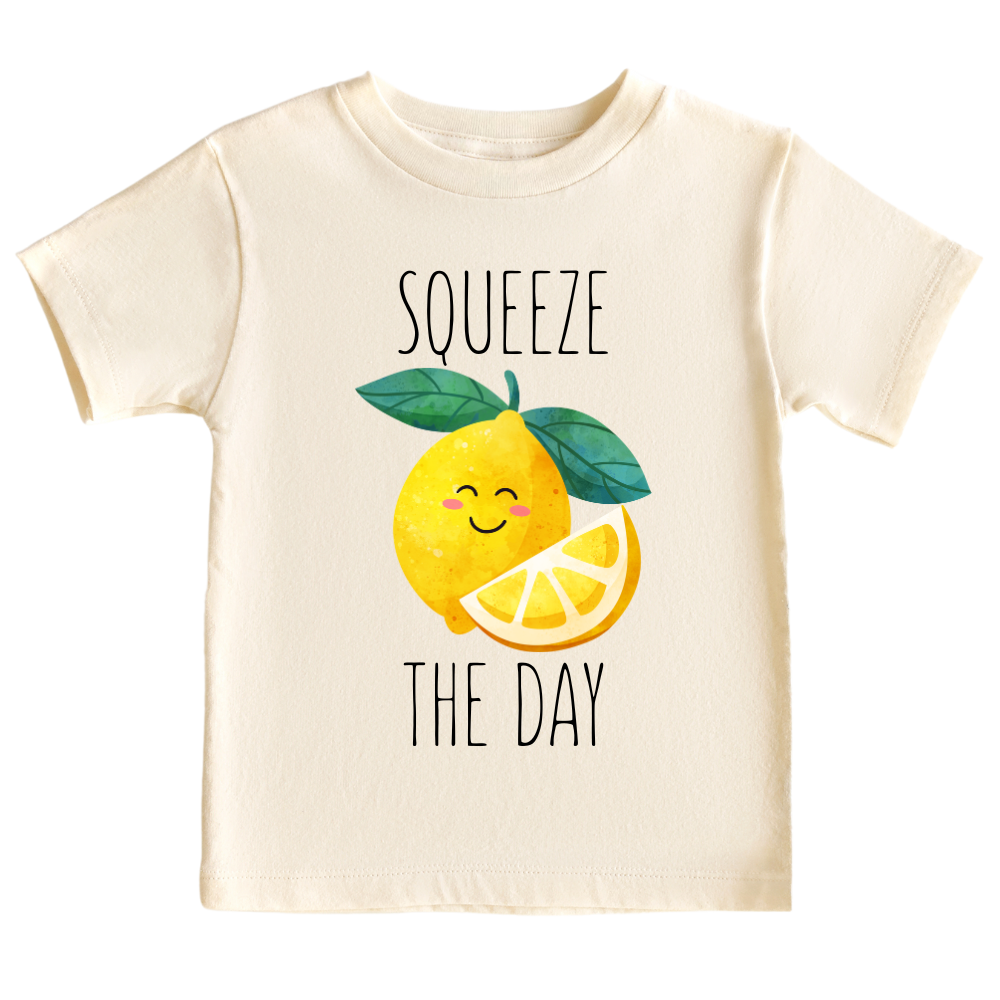 Natural toddler t-shirt showcasing a playful printed graphic of a lemon with the text 'Squeeze The Day.' Explore this vibrant and motivational tee, perfect for adding a burst of positivity to your child's wardrobe.