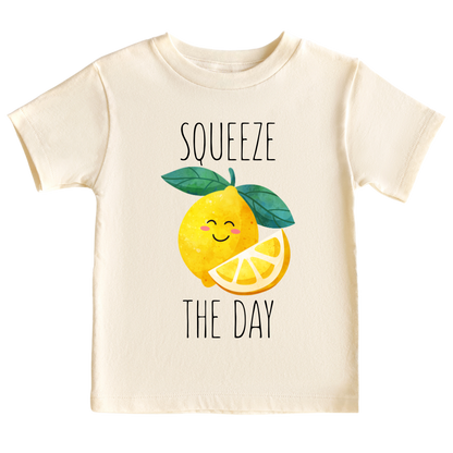 Natural toddler t-shirt showcasing a playful printed graphic of a lemon with the text 'Squeeze The Day.' Explore this vibrant and motivational tee, perfect for adding a burst of positivity to your child's wardrobe.