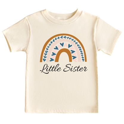 A kid's t-shirt with a boho printed graphic of a colorful rainbow and the text 'Little Sister.' This enchanting t-shirt celebrates the arrival of a precious little sister.