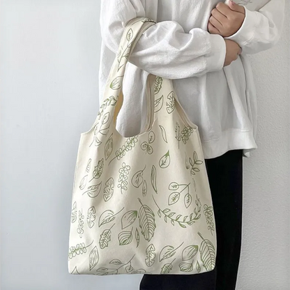 front view of beige color canvas tote bag with green prints of different leaf icons